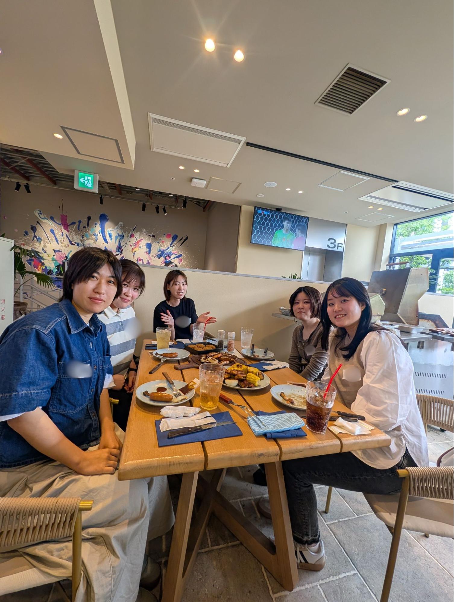 会社のBBQイベントで、テーブルを囲んで食事や会話を楽しむAvintonジャパンの社員たち