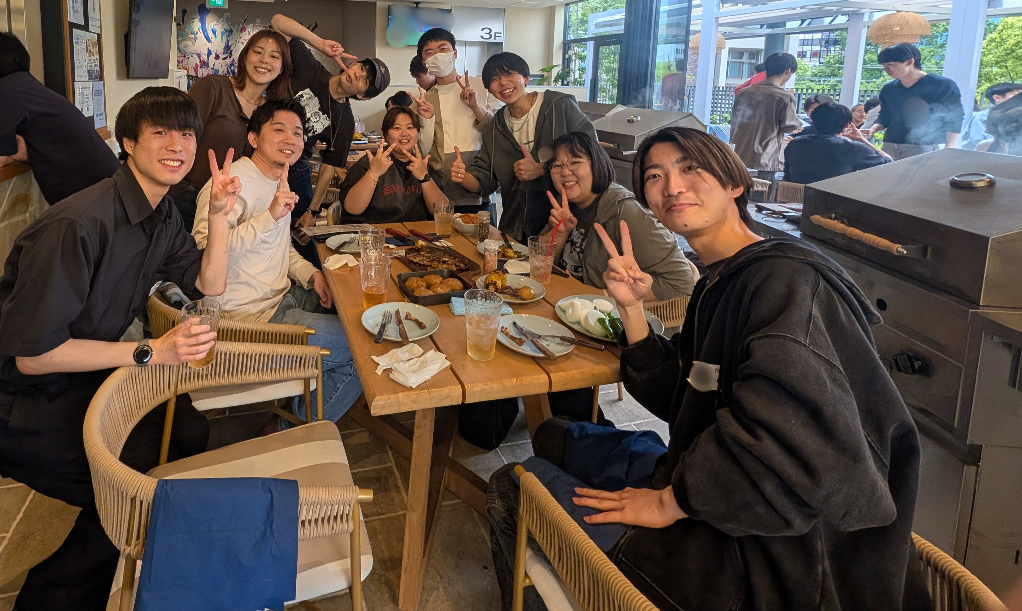 BBQ会場のテーブルを囲んで、笑顔でピースサインをする社員たち